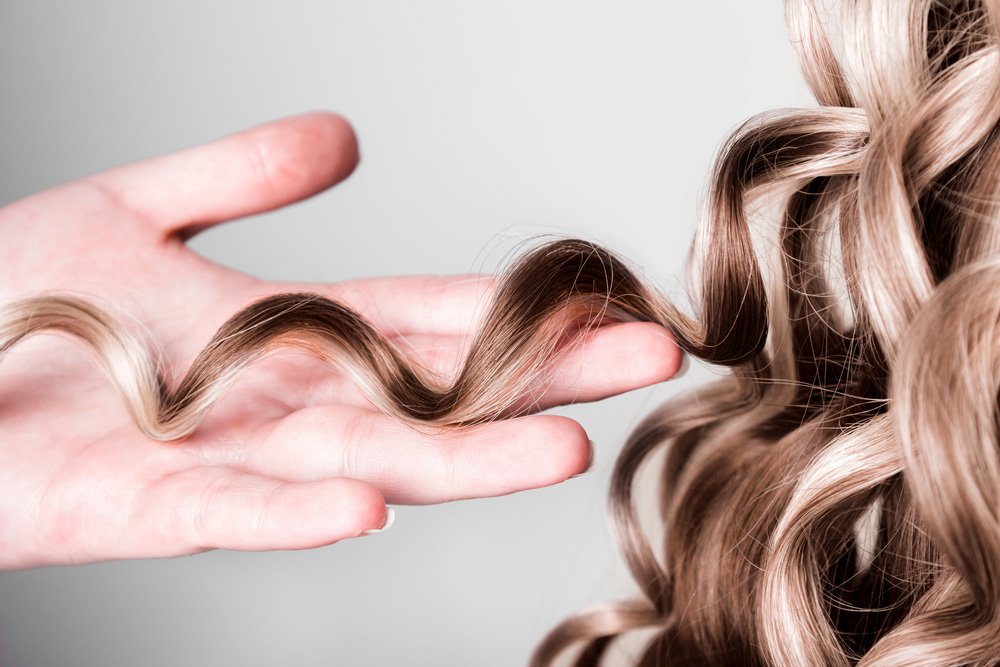 Holding A Strand Of Curly Blond Hair